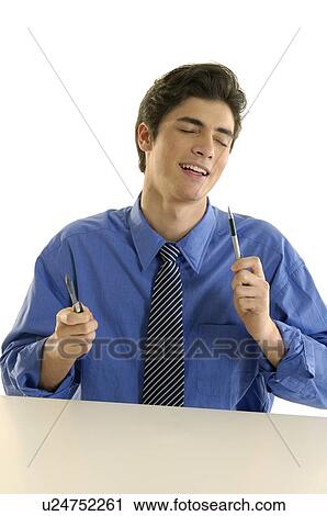 Businessman sitting at a desk and holding two pens View Large Photo Image Stock Image - Businessman sitting at a desk and holding two pens. Fotosearch