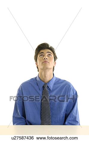 Stock Photograph - Businessman sitting at a desk and looking up in an office. Fotosearch
