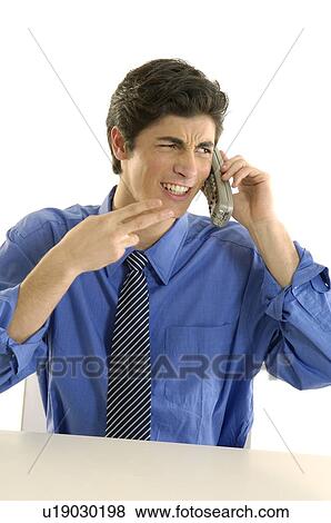 Businessman talking on a cordless phone and making a gun sign View Large Photo Image Stock Photo - Businessman talking on a cordless phone and making a gun sign. Fotosearch