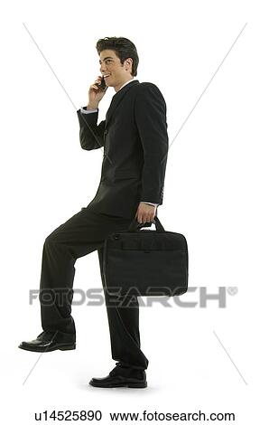 Stock Image - Businessman talking on a mobile phone and standing on one leg. Fotosearch