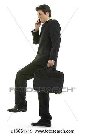 Stock Photography - Businessman talking on a mobile phone and standing on one leg. Fotosearch