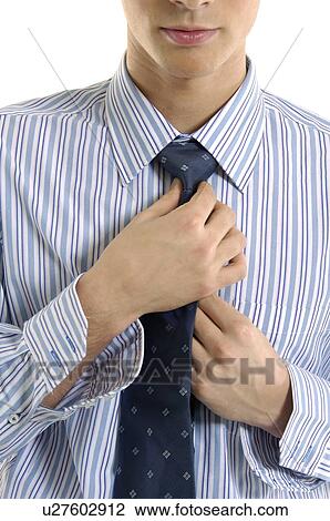 Stock Image - Close-up of a businessman adjusting his tie. Fotosearch