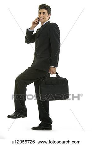 Stock Photograph - Portrait of a businessman talking on a mobile phone and standing on one leg. Fotosearch
