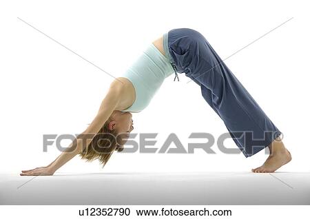 Stock Image - Young woman in downward facing dog position. Fotosearch