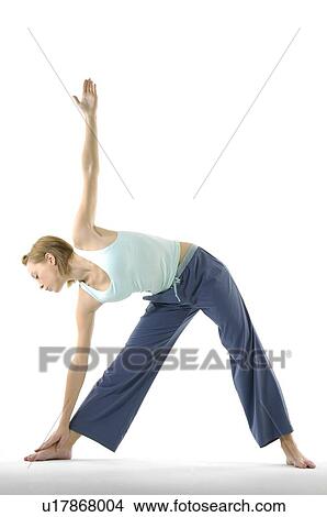 Picture - Young woman standing in triangle position. Fotosearch