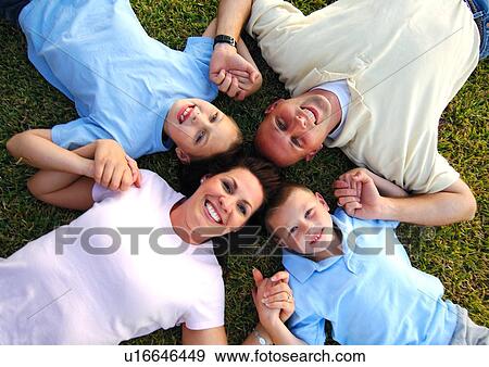 Stock Photo - High angle view of a mid adult couple lying on grass in a circle with their two sons. Fotosearch
