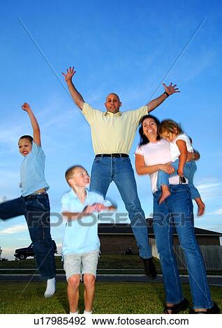 Stock Image - Low angle view of a mid adult couple with their children smiling. Fotosearch