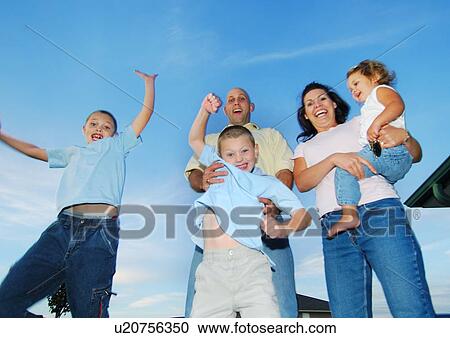 Low angle view of a mid adult couple standing with their children and smiling View Large Photo Image Stock Image - Low angle view of a mid adult couple standing with their children and smiling. Fotosearch