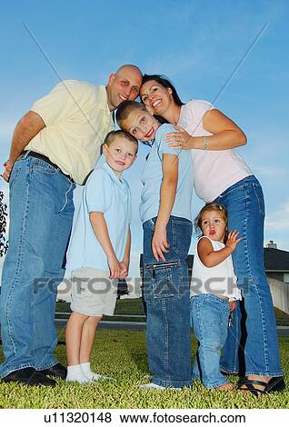Stock Photo - Low angle view of a mid adult couple standing with their children and smiling. Fotosearch