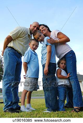 Stock Photography - Low angle view of a mid adult couple standing with their children and smiling. Fotosearch