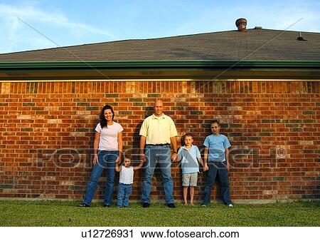 Mid adult couple standing in front of a brick wall with their three children View Large Photo Image Stock Image - Mid adult couple standing in front of a brick wall with their three children. Fotosearch