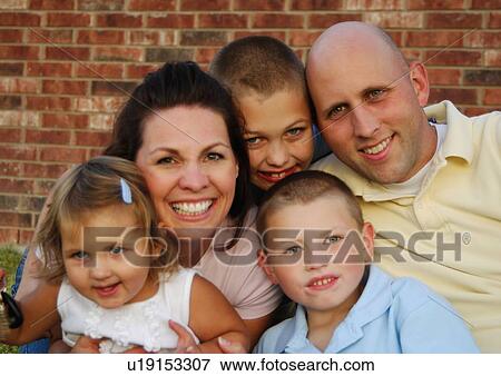 Stock Photo - Portrait of a mid adult couple smiling with their three children. Fotosearch