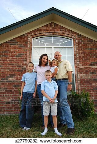 Stock Image - Portrait of a mid adult couple standing with their three children and smiling. Fotosearch