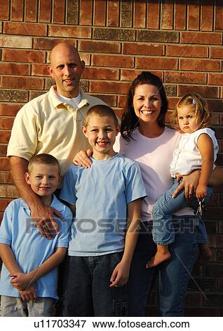 Portrait of a mid adult couple standing with their three children and smiling View Large Photo Image Stock Photo - Portrait of a mid adult couple standing with their three children and smiling. Fotosearch