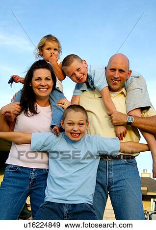 Stock Photo - Portrait of a mid adult couple standing with their children and smiling. Fotosearch