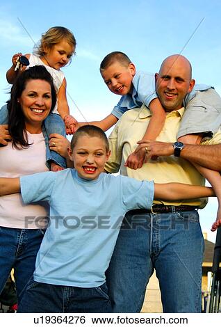 Portrait of a mid adult couple standing with their children and smiling View Large Photo Image Stock Photograph - Portrait of a mid adult couple standing with their children and smiling. Fotosearch