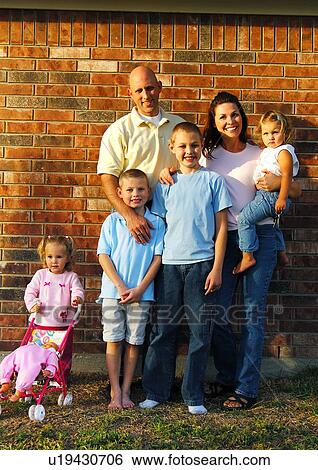 Portrait of a mid adult couple standing with their four children and smiling View Large Photo Image Stock Photograph - Portrait of a mid adult couple standing with their four children and smiling. Fotosearch