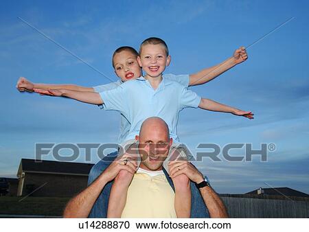 Portrait of a mid adult man carrying their two sons on his shoulders View Large Photo Image Stock Image - Portrait of a mid adult man carrying their two sons on his shoulders. Fotosearch