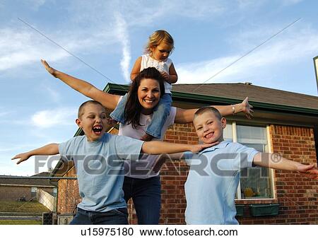 Stock Image - Portrait of a mid adult woman playing with her three children. Fotosearch