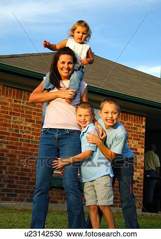 Stock Image - Portrait of a mid adult woman playing with her three children. Fotosearch