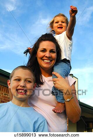 Stock Image - Portrait of a mid adult woman smiling with her son and daughter. Fotosearch