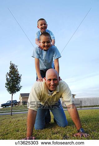 Stock Image - Two boys riding on their father's back. Fotosearch