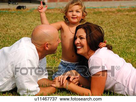 Stock Photo - Mid adult couple smiling in a park with their daughter. Fotosearch