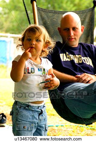Portrait of a daughter with her father sitting in a hammock behind him View Large Photo Image Stock Image - Portrait of a daughter with her father sitting in a hammock behind him. Fotosearch