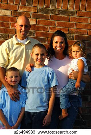 Stock Image - Portrait of a mid adult couple standing with their children. Fotosearch
