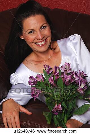 Portrait of a mid adult woman holding a bouquet of flowers and smiling View Large Photo Image Stock Photograph - Portrait of a mid adult woman holding a bouquet of flowers and smiling. Fotosearch