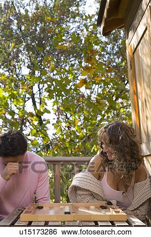 Stock Photograph - Couple playing backgammon outdoors smiling.. Fotosearch