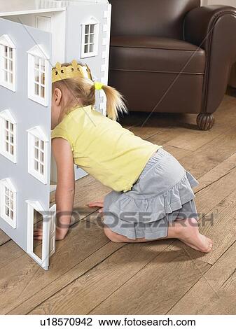 Stock Image - Little girl playing with a doll house. Fotosearch