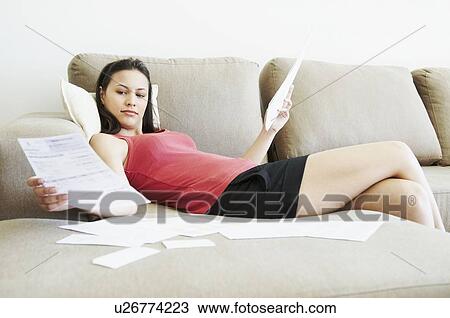 Stock Image - Reclined woman looking at paperwork. Fotosearch