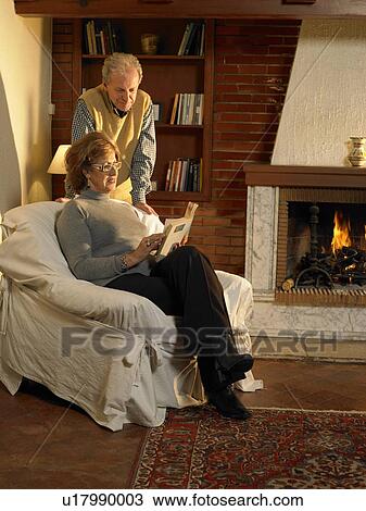 Senior couple looking at book in living room View Large Photo Image Stock Image - Senior couple looking at book in living room. Fotosearch