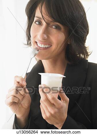 Woman eating yoghurt, smiling View Large Photo Image Picture - Woman eating yoghurt, smiling. Fotosearch
