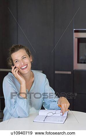 Stock Photo - Woman in kitchen talking on phone.. Fotosearch