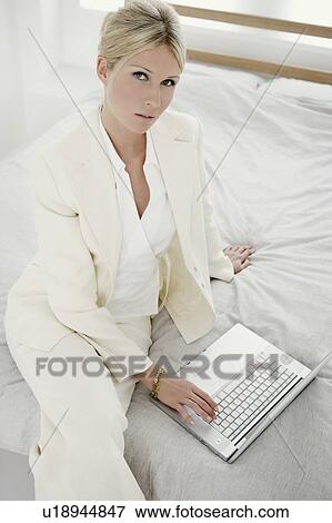 Stock Photo - Woman with laptop on bed.. Fotosearch