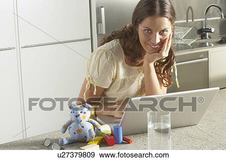 Stock Photo - Young business woman working from home kitchen.. Fotosearch