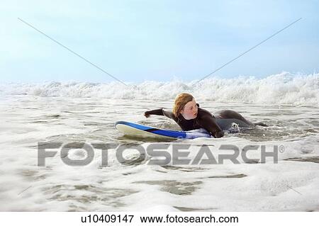 Stock Photo - Female lying on surfboard, paddling. Fotosearch