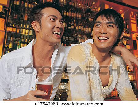 Stock Photo - Asian Ethnicity, Beer, Bar Counter, Bar, Arm Around. Fotosearch