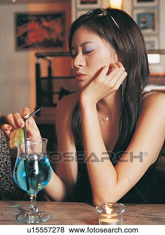Stock Photo - Eyes Closed, Indoor, Cheerful, One Young Woman Only, Drinking Straw, Bar. Fotosearch