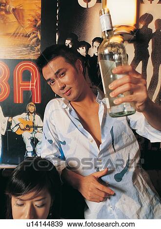 Stock Photo - Young Adult, Japanese Ethnicity, Cheerful, Wine Bottle, Indoor, Young Couple, Casual Clothing. Fotosearch