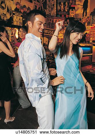 Stock Image - Youth Culture, Leisure Activity, Dancing, Young Couple, Black Hair, Evening Wear, Button Down Shirt. Fotosearch