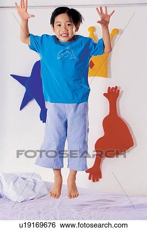 Stock Photograph - arms outstretched, bed room, asian ethnicity, 5-6 years. Fotosearch