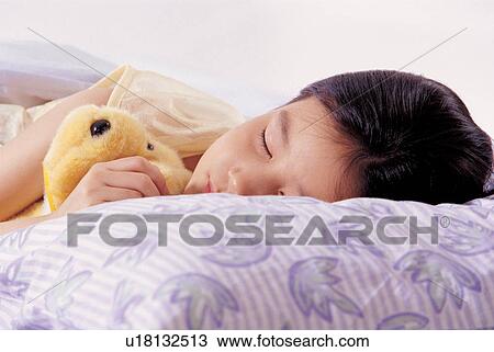 Stock Image - bedroom, stuffed toy, sleeping, asian ethnicity. Fotosearch