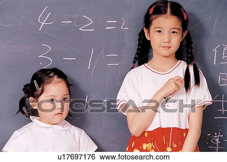 Stock Photograph - learning, side by side, black board, looking away, children, only girls, childhood. Fotosearch