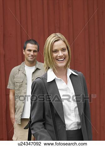 Stock Image - Businesswoman and man by country cottage. Fotosearch
