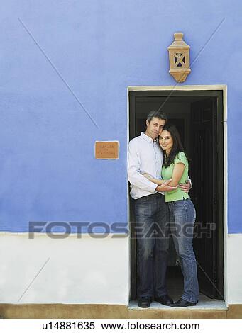 Stock Photography - Couple embracing in doorway, smiling, portrait. Fotosearch