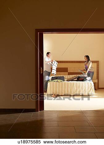 Stock Photography - Couple unpacking suitcases in hotel room. Fotosearch