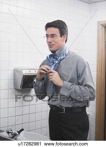 Man reflected in office washroom mirror doing up his tie View Large Photo Image Stock Image - Man reflected in office washroom mirror doing up his tie. Fotosearch